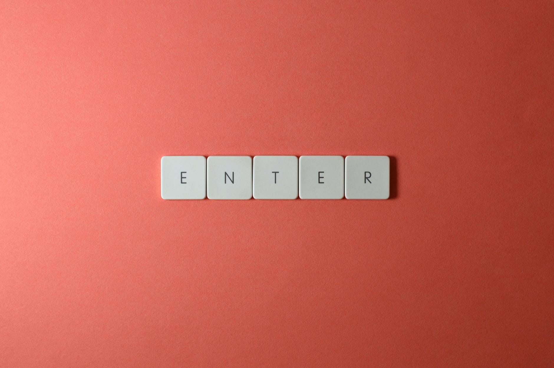 Pięć klawiszy z literami ENTER na tle w kolorze koralowym