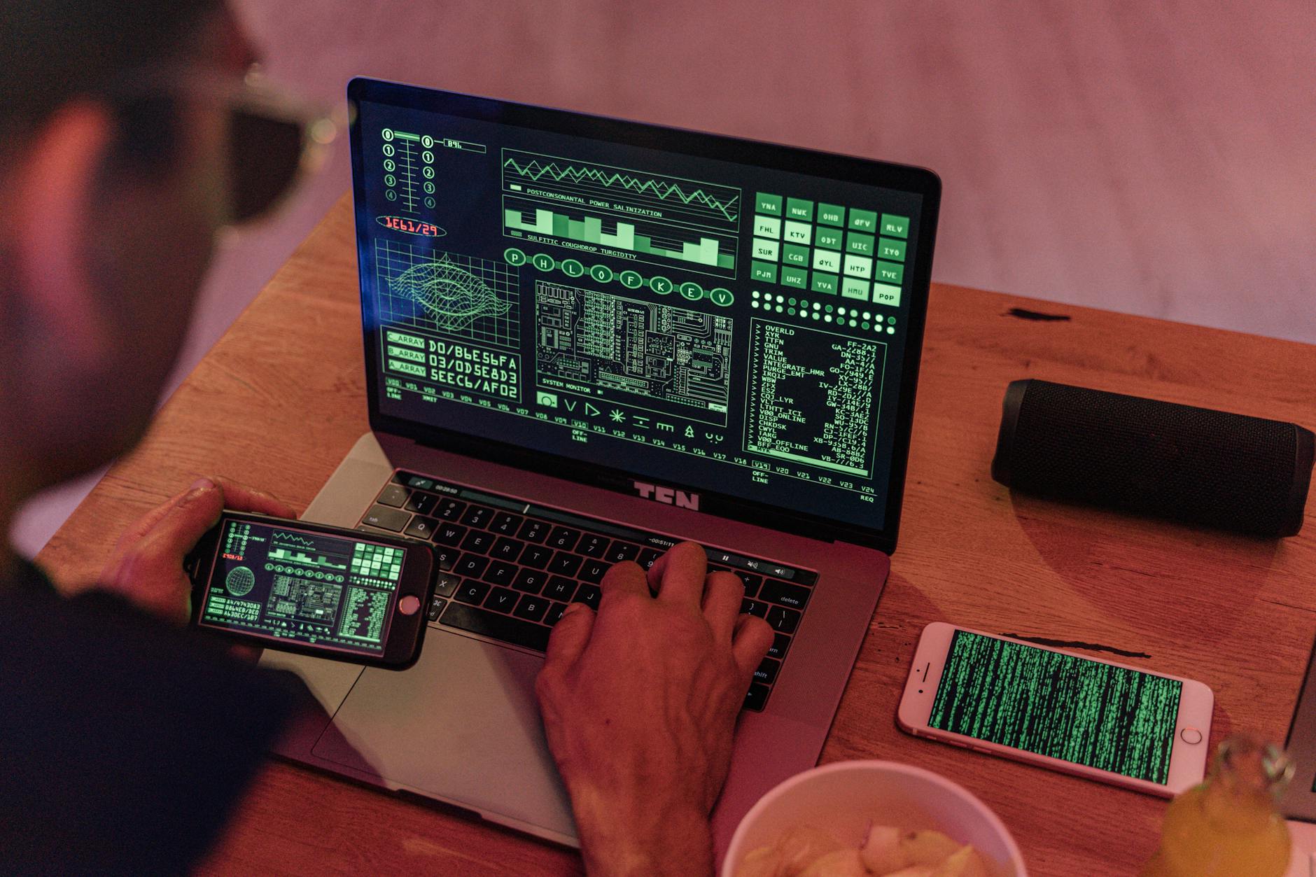 Mężczyzna analizuje oprogramowanie cyberbezpieczeństwa na laptopie i telefonie